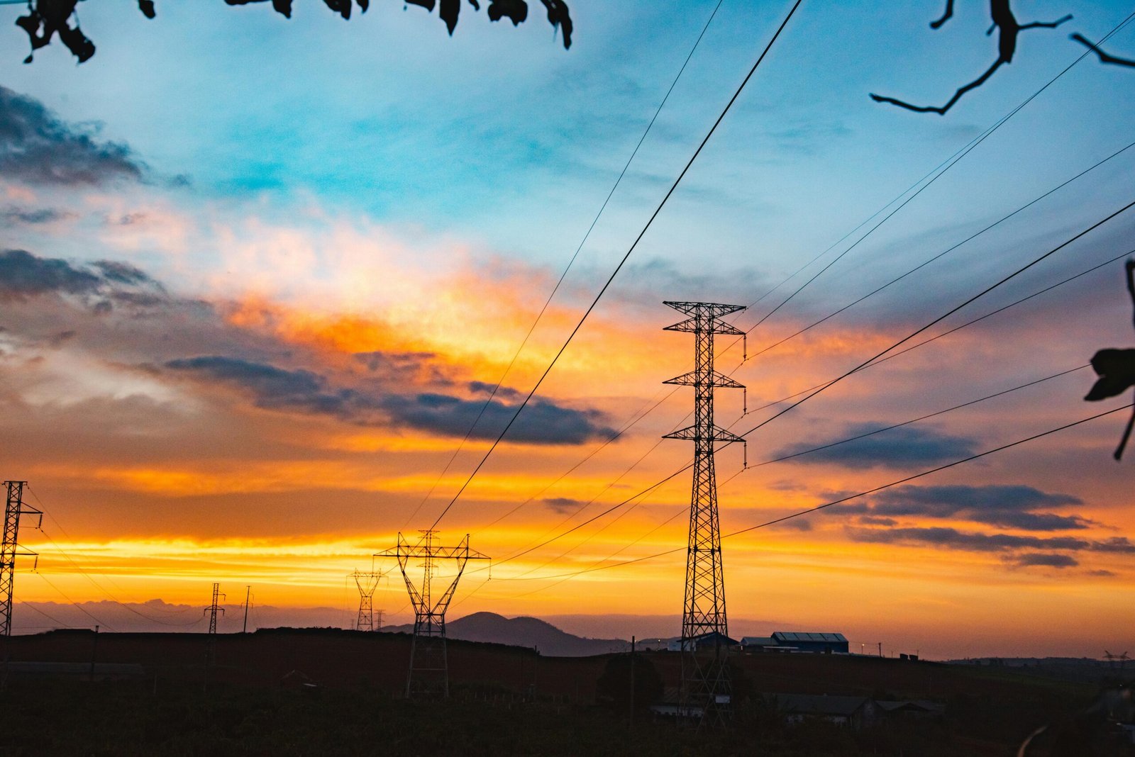 Silhouette of power lines against a vibrant sunset sky, symbolizing energy and nature.